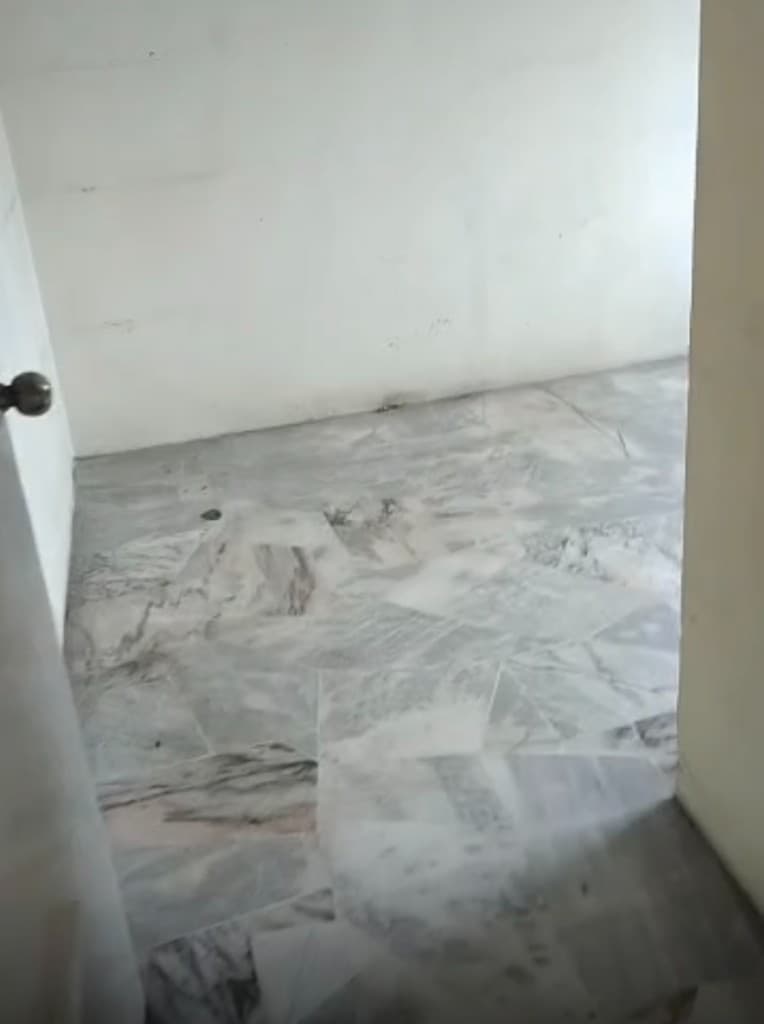 Empty bedroom after full apartment clear-out, marble floor and bare walls