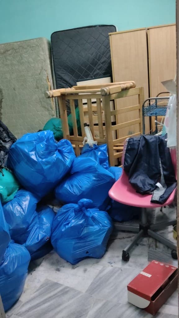 Room with blue disposal bags, mattresses, and wardrobes before removal